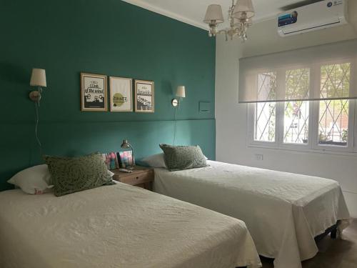 2 Betten in einem Zimmer mit grünen Wänden und einem Fenster in der Unterkunft Casa Gutiérrez in Godoy Cruz