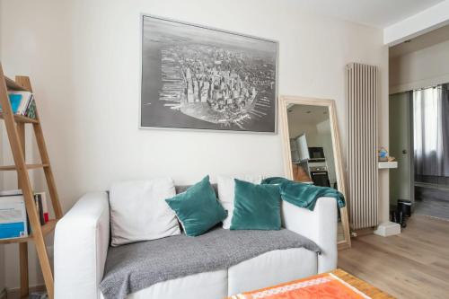 una sala de estar con un sofá blanco con almohadas verdes en Appartement Maurice - Welkeys en Montrouge