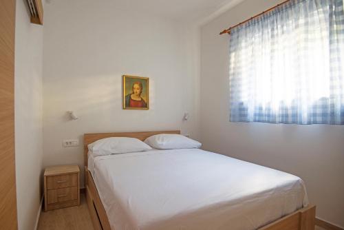 niewielka sypialnia z łóżkiem i oknem w obiekcie Apartmani Tomica w mieście Jesenice