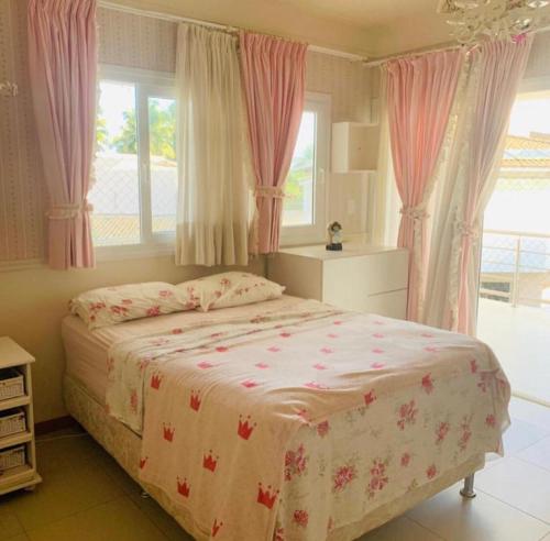 een slaapkamer met een groot bed en roze gordijnen bij Casa Villas in Lauro de Freitas