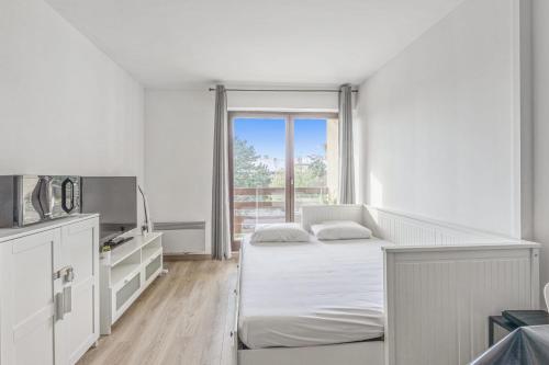 une chambre blanche avec deux lits et une fenêtre dans l'établissement Appartement Romance - Welkeys, à Cabourg