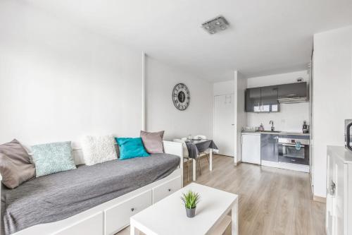 un salon avec un canapé et une cuisine dans l'établissement Appartement Romance - Welkeys, à Cabourg