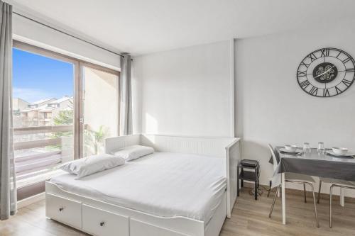 - une chambre avec un lit, un bureau et une horloge dans l'établissement Appartement Romance - Welkeys, à Cabourg