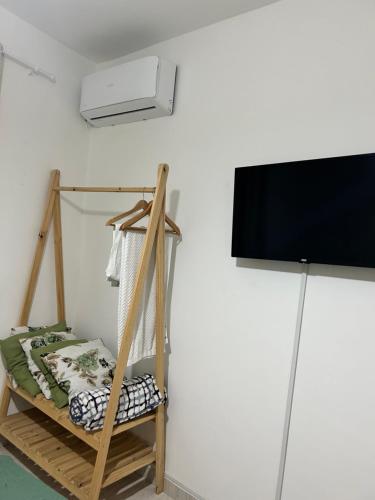 Cette chambre comprend une télévision, un lit et une étagère. dans l'établissement Pousada na fazenda! Venha descansar!, à Serra