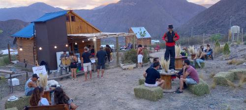 a group of people sitting and standing in front of a building at Cabañas Piquillin Potrerillos Mendoza in Potrerillos