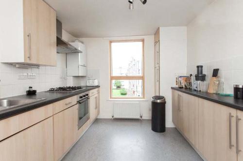 a white kitchen with a sink and a window at Double Bedroom with ensuite Regents Canal in London