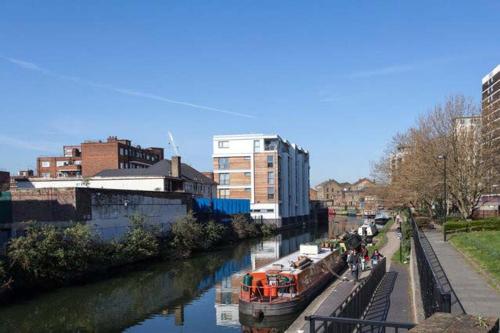 a boat is docked on a river in a city at Double Bedroom with ensuite Regents Canal in London