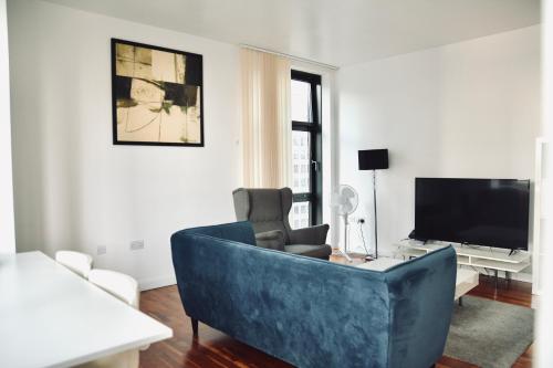 a living room with a blue couch and a tv at 2 Bedroom Discovery Dock in London
