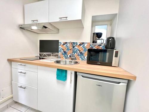 une petite cuisine avec un évier et un micro-ondes dans l'établissement Le petit Penon ~ T1 Bis avec parking /clim /Fibre, à Saint-Georges-lès-Baillargeaux