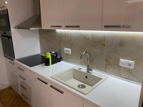 a white kitchen with a sink and a counter at Regal Comfort Apartment in Pirot