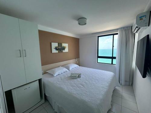 a bedroom with a white bed with a window at Flat para 2, de frente para o Mar in Natal