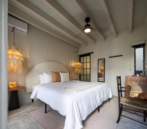 sypialnia z dużym białym łóżkiem i krzesłem w obiekcie HOLT Hotel del Pueblito w mieście San Miguel de Allende