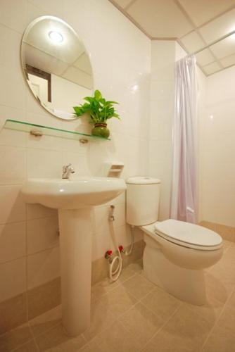 a bathroom with a toilet and a sink and a mirror at Sitara Place Serviced Apartment & Hotel in Bangkok