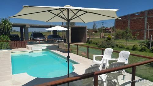 een zwembad met 2 stoelen en een parasol bij Posada del Flamenco in Miramar
