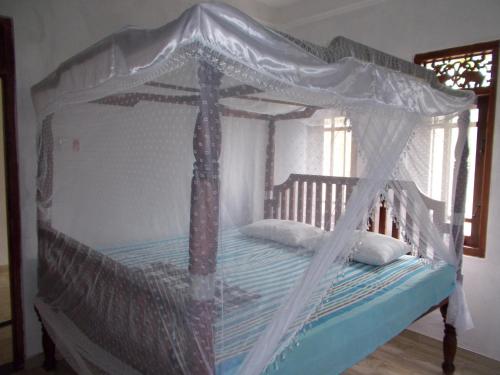 a wooden bed with a canopy in a room at Leisure Home Mirissa in Mirissa