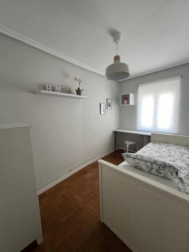 een witte slaapkamer met een bed en een raam bij Piso acogedor cerca del centro. in Burgos