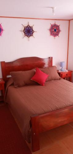 1 dormitorio con cama de madera y almohadas rojas en Cabañas paraíso el Yacal, en El Bolsico