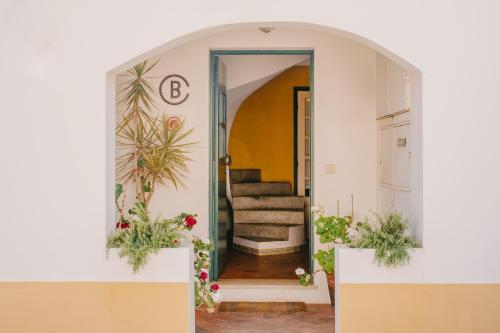 a hallway with a door leading to a staircase with flowers at Lote 30 in Vila Nova de Milfontes