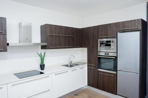 a kitchen with wooden cabinets and a stainless steel refrigerator at Villa Santiago in Praia