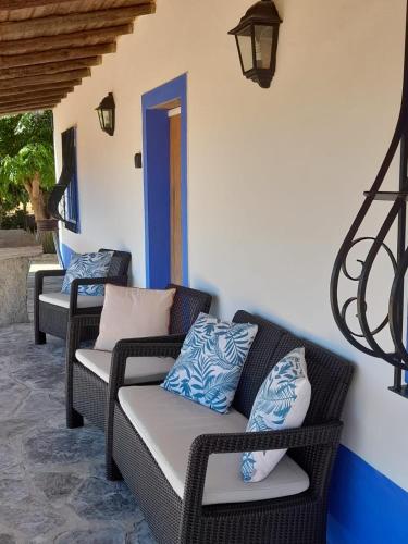 a patio with three wicker chairs and a blue door at Monte do Ribeiro Baço - Monsaraz in Monsaraz
