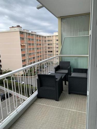 un balcon avec des chaises et des tables sur un immeuble dans l'établissement Appartement à 50 mètres de la plage, à Cagnes-sur-Mer