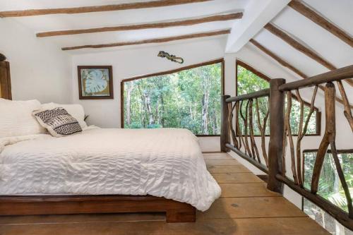 a bedroom with a bed and a large window at Casa de la Selva-Jungle Getaway with cenotes in Playa del Carmen