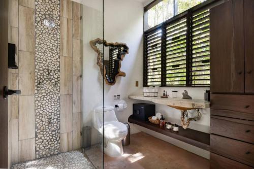 a bathroom with a toilet and a sink and a mirror at Casa de la Selva-Jungle Getaway with cenotes in Playa del Carmen