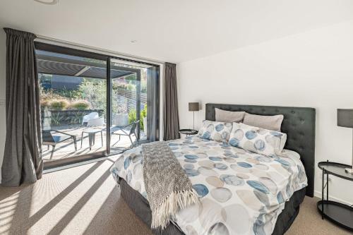 a bedroom with a large bed and a balcony at Noir South Retreat in Wanaka