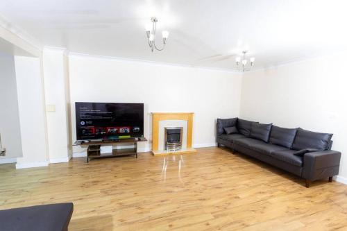 a living room with a black couch and a flat screen tv at Spacious and Luxurious 5 Bedroom Town House for 9 in Kent