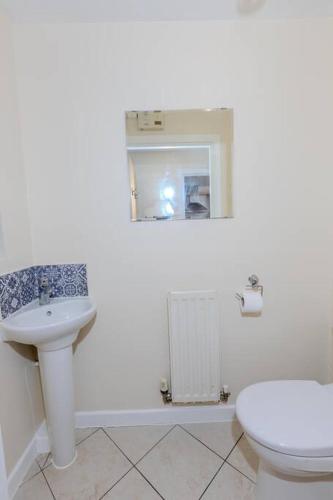 a white bathroom with a sink and a toilet at Spacious and Luxurious 5 Bedroom Town House for 9 in Kent