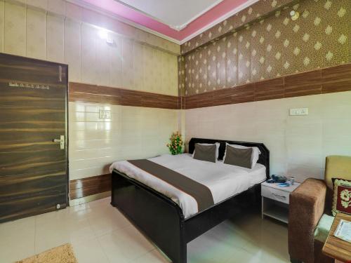 1 dormitorio con 1 cama grande y 1 silla en Collection O Hotel Paradise And Restaurant, en Kāshīpur