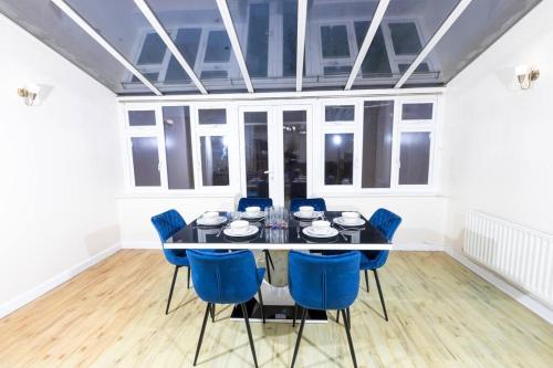 a dining room with a black table and blue chairs at Spacious and Luxurious 5 Bedroom Town House for 9 in Kent