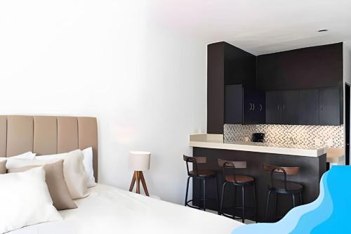 a bedroom with a bed and a bar with stools at Minimalist Studio with Pool and FREE Scooter in Cozumel