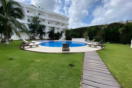 a swimming pool in front of a large building at Minimalist Studio with Pool and FREE Scooter in Cozumel