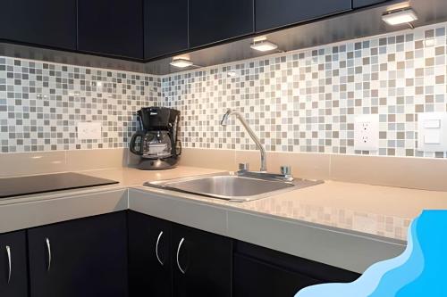 a kitchen with a sink and black cabinets at Minimalist Studio with Pool and FREE Scooter in Cozumel