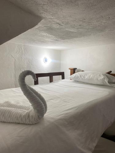a snake laying on top of a white bed at Hospedaje casa Chisakui- Acogedora Casa en Villa de Leyva in Villa de Leyva