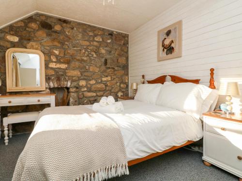 a bedroom with a bed and a stone wall at Pippin in St Ives