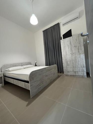 een witte slaapkamer met een bed en een raam bij Homeshop in Agira