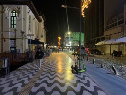a person standing on a city street at night at Deluxe Apartment at the seaside in Pasaport Alsancak Izmir in Konak
