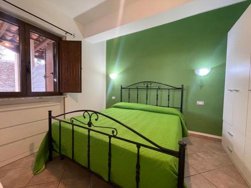 ein grünes Schlafzimmer mit einem Bett und einem Fenster in der Unterkunft Appartamenti Pousada Michelino in Parghelia