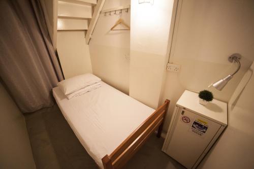 Piccola camera con letto piccolo e piccolo frigorifero. di Blanc Inn a Singapore