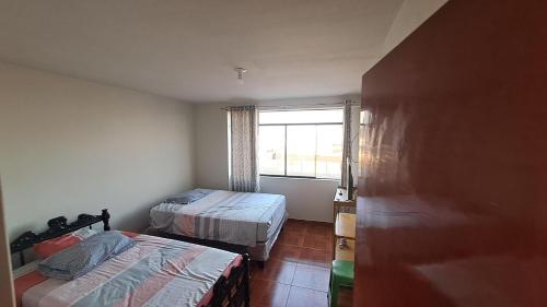 um pequeno quarto com 2 camas e uma janela em Casa de Verano en Mollendo em Mollendo