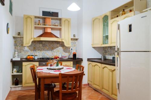 a kitchen with a table and a white refrigerator at Le Maioliche in Saponara Villafranca