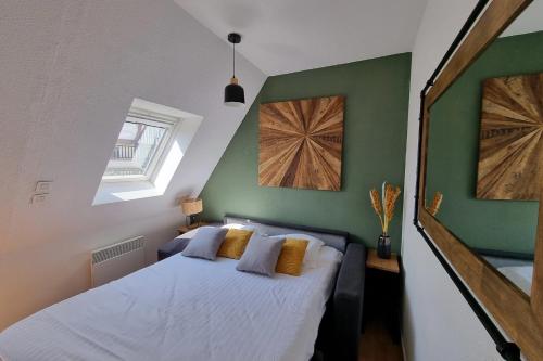 a bedroom with a bed with white sheets and green walls at Studio cocooning petite vue mer in Cabourg
