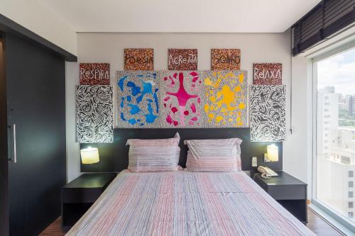 a bedroom with a bed with three paintings on the wall at LFlats no Hotel Stella Vega (EX-Mercury Ibirapuera) in Sao Paulo