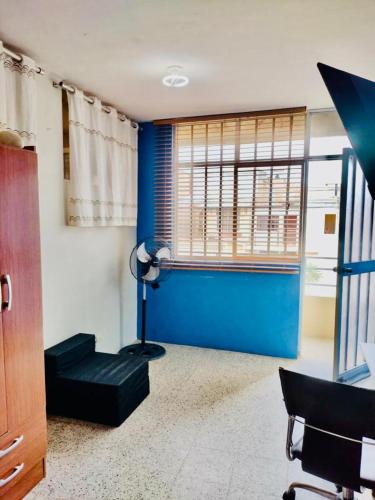 ein Wohnzimmer mit blauen Wänden und einer schwarzen Couch in der Unterkunft Habitación en Chiclayo in Chiclayo