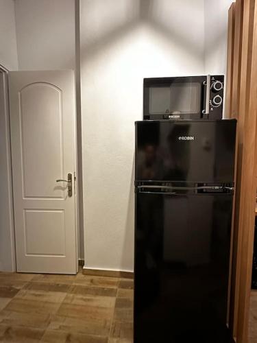 a black refrigerator with a microwave on top of it at Tiny Nest Sindos in Síndos