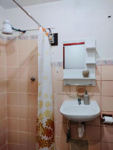 ein Bad mit einem Waschbecken, einem Spiegel und einer Dusche in der Unterkunft Habitación en Chiclayo in Chiclayo