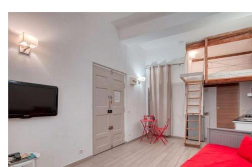 un salon avec un lit et une télévision sur un mur dans l'établissement Très beau studio idéalement situé centre ville, à La Ciotat