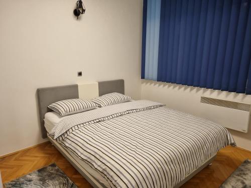 a bedroom with a bed with striped sheets and a window at Apartment Urban Nest in Zenica
